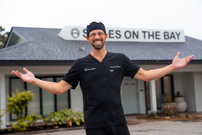 Dr. Thompson with open arms in front of office sign